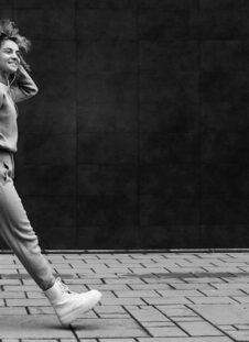 Young fashionable woman waking on the street and listening to music